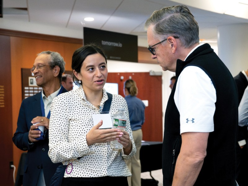 MIT AeroAstro Department members Evana Gizzi (left) and Olivier de Weck (right) chat in front of the department’s exhibit on a game called GEOPatrol that simulates non-cooperative interactions in space between two space actors. Credit: Nicole Fandel/MIT Lincoln Laboratory