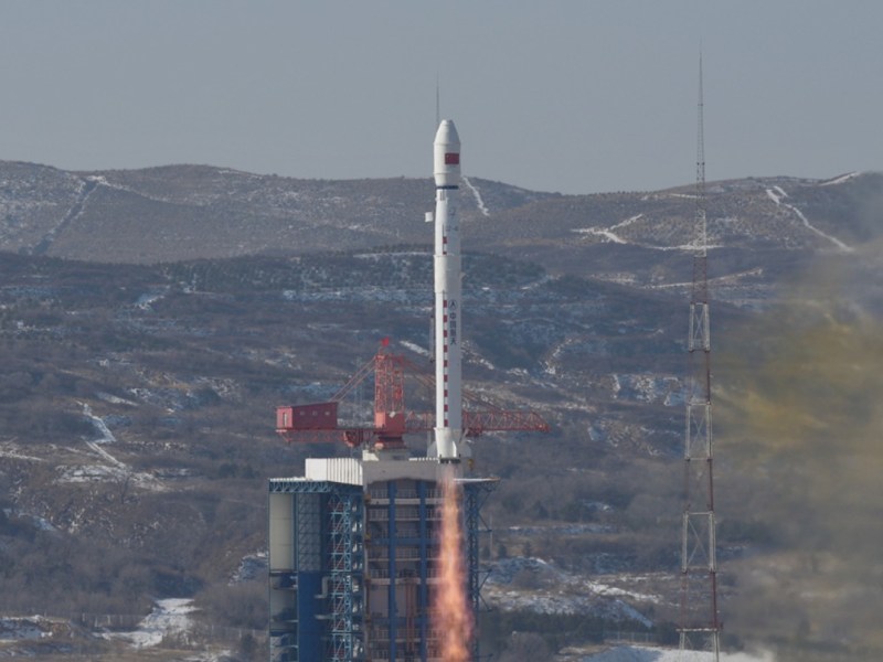 A Long March 4B lifts off carrying the Ziyuan-3 (04) remote sensing satellite, Dec. 16 (UTC), 2025, climbing above the snow-dusted hills surrounding Taiyuan spaceport.